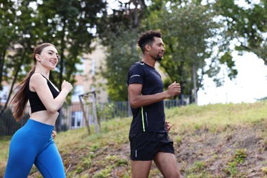 Photo of Couple in sportswear running in park, low angle view. Space for text