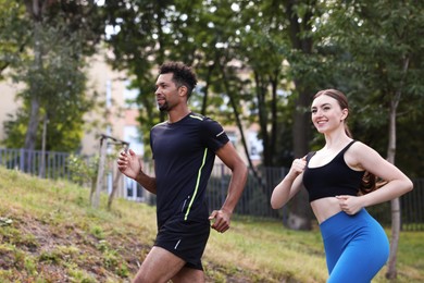 Photo of Smiling couple in sportswear running in park