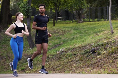 Photo of Couple in sportswear running in park, low angle view. Space for text
