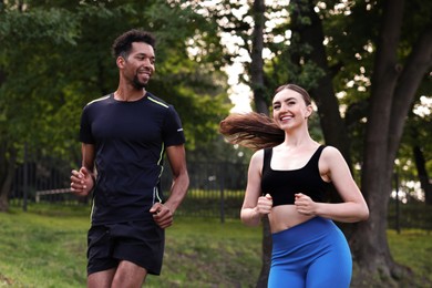 Photo of Smiling couple in sportswear running in park