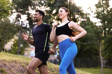 Photo of Smiling couple in sportswear running in park, low angle view