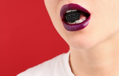 Photo of Woman with beautiful lips makeup and blackberry on red background, closeup. Space for text