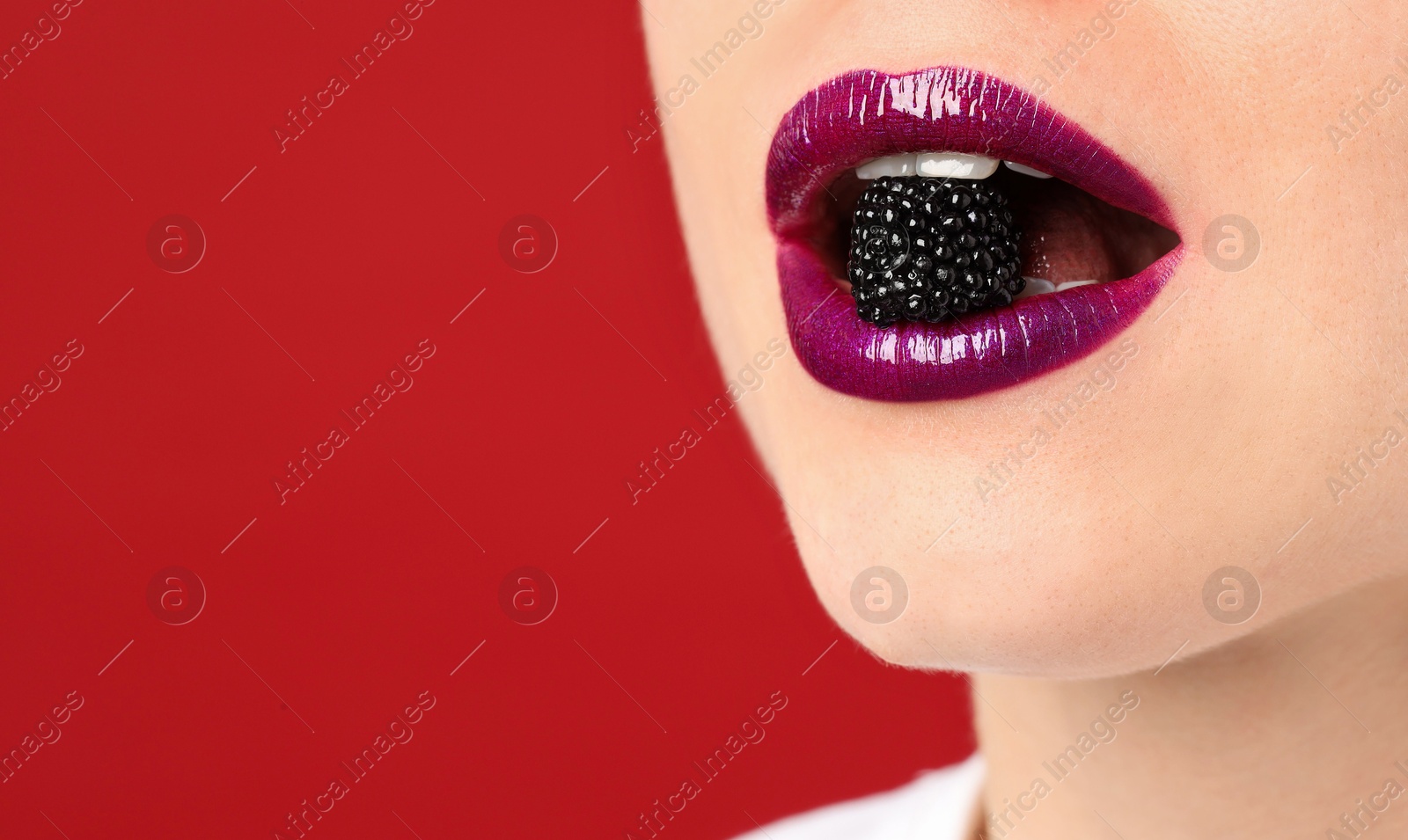 Woman with beautiful lips makeup and blackberry on red background, closeup. Space for text Photo of Woman with beautiful lips makeup and blackberry on red background, closeup. Space for text