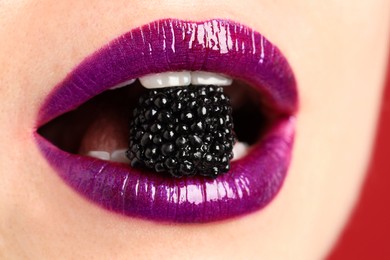 Photo of Woman with beautiful lips makeup and blackberry on red background, closeup