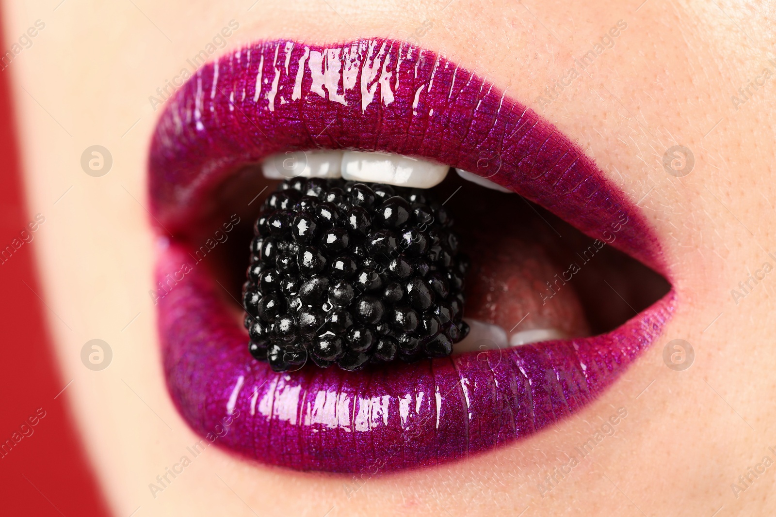 Woman with beautiful lips makeup and blackberry on red background, closeup Photo of Woman with beautiful lips makeup and blackberry on red background, closeup