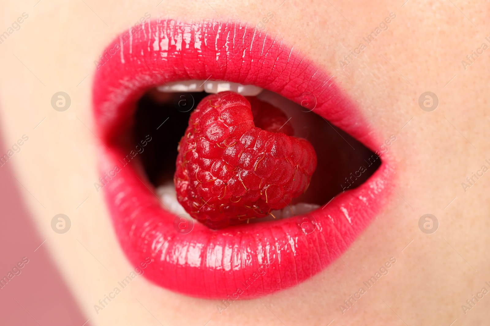 Woman with beautiful lips makeup and raspberry on dusty pink background, closeup Photo of Woman with beautiful lips makeup and raspberry on dusty pink background, closeup
