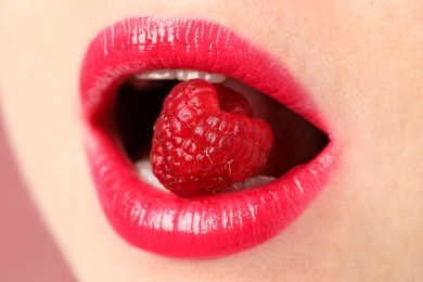 Photo of Woman with beautiful lips makeup and raspberry on dusty pink background, closeup