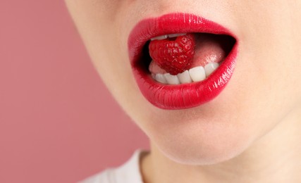 Photo of Woman with beautiful lips makeup and raspberry on dusty pink background, closeup. Space for text