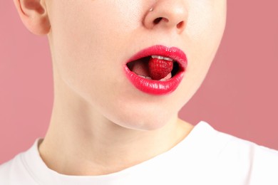 Photo of Woman with beautiful lips makeup and raspberry on dusty pink background, closeup
