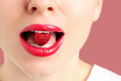 Photo of Woman with beautiful lips makeup and raspberry on dusty pink background, closeup