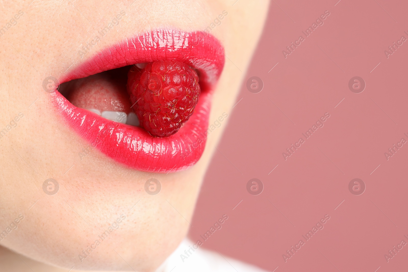 Woman with beautiful lips makeup and raspberry on dusty pink background, closeup. Space for text Photo of Woman with beautiful lips makeup and raspberry on dusty pink background, closeup. Space for text