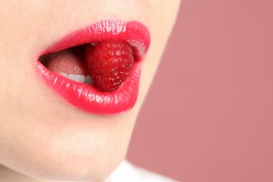 Photo of Woman with beautiful lips makeup and raspberry on dusty pink background, closeup. Space for text