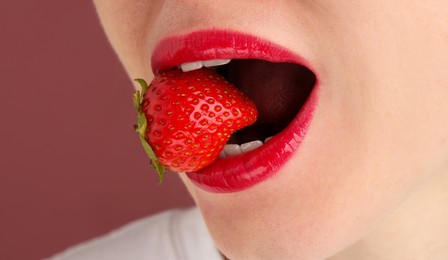 Photo of Woman with beautiful lips makeup and strawberry on dusty pink background, closeup. Space for text