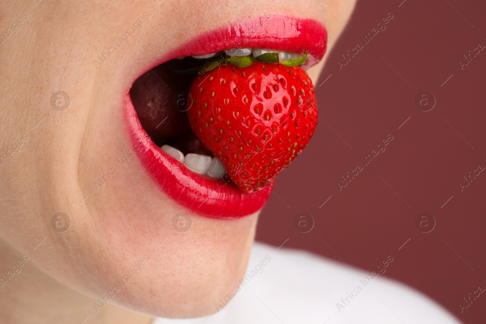 Woman with beautiful lips makeup and strawberry on dusty pink background, closeup. Space for text Photo of Woman with beautiful lips makeup and strawberry on dusty pink background, closeup. Space for text