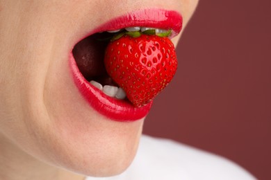 Photo of Woman with beautiful lips makeup and strawberry on dusty pink background, closeup. Space for text
