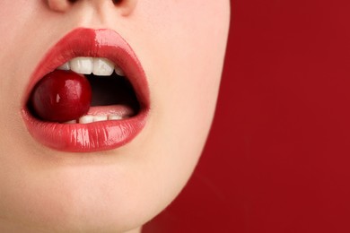 Photo of Woman with beautiful lips makeup and cherry on red background, closeup. Space for text