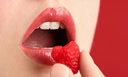 Photo of Woman with beautiful lips makeup and raspberry on red background, closeup