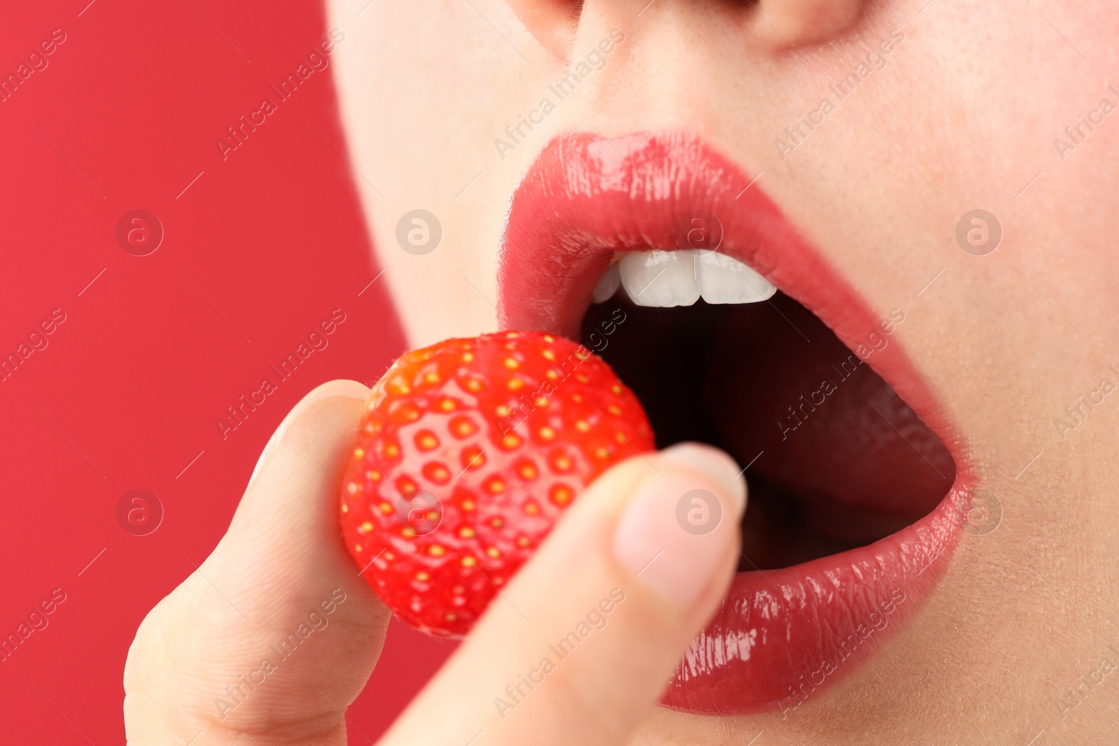 Woman with beautiful lips makeup and strawberry on red background, closeup Photo of Woman with beautiful lips makeup and strawberry on red background, closeup