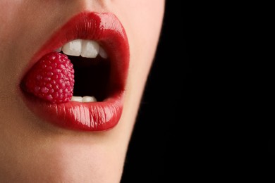 Photo of Woman with beautiful lips makeup and raspberry candy on black background, closeup. Space for text