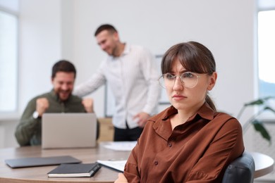 Photo of Woman feeling jealous of her colleague's success in office, selective focus