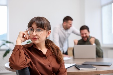 Photo of Woman feeling jealous of her colleague's success in office, selective focus