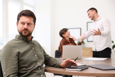 Photo of Man feeling jealous of his colleague's success in office, selective focus
