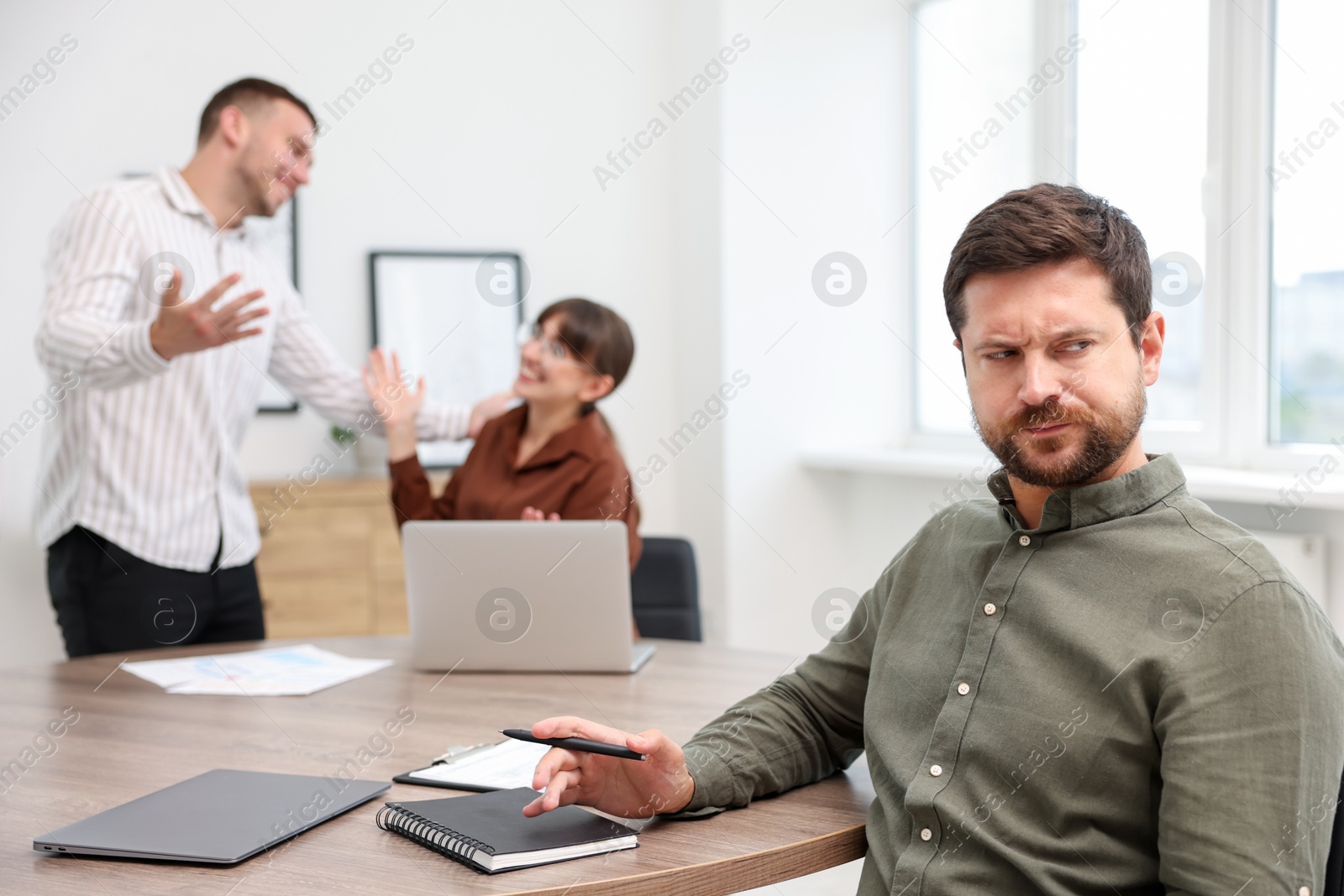 Photo of Man feeling jealous of his colleague's success in office, selective focus