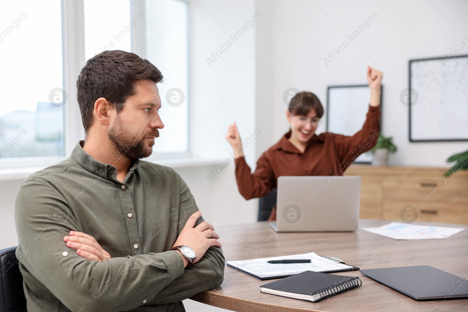 Photo of Man feeling jealous of his colleague's success in office, selective focus