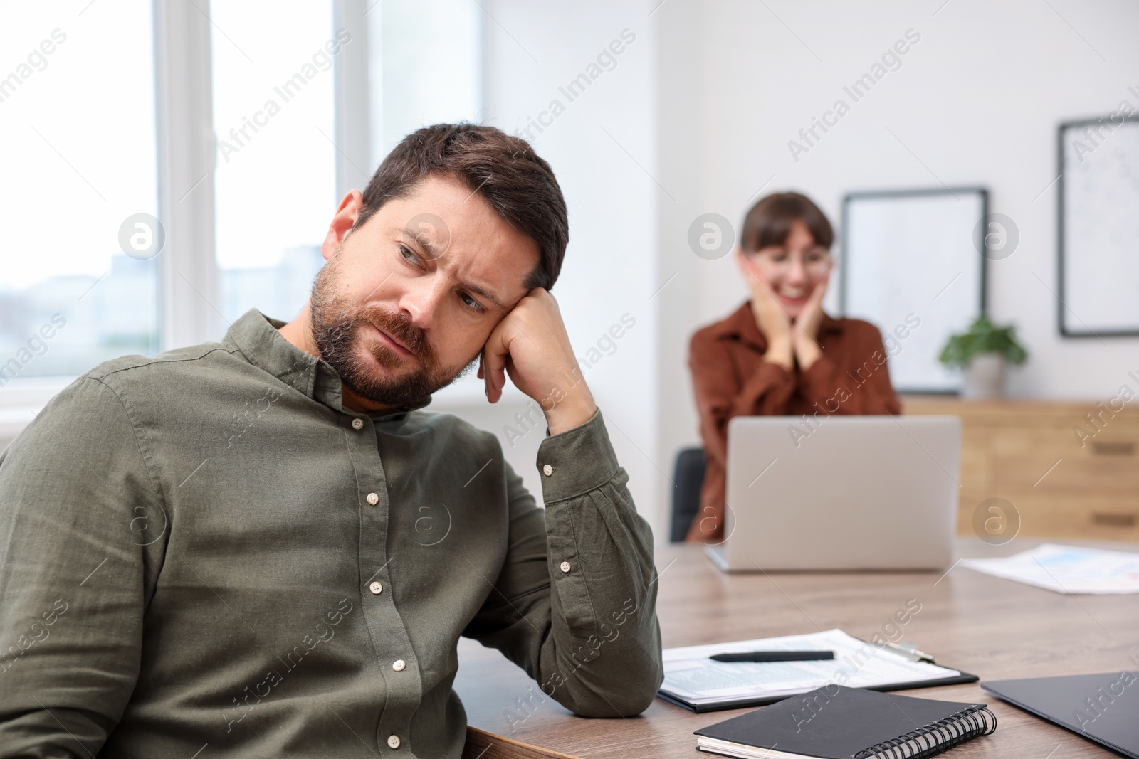 Photo of Man feeling jealous of his colleague's success in office, selective focus