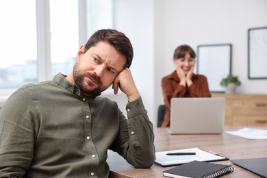 Photo of Man feeling jealous of his colleague's success in office, selective focus