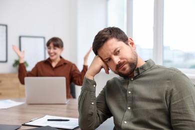 Photo of Man feeling jealous of his colleague's success in office, selective focus