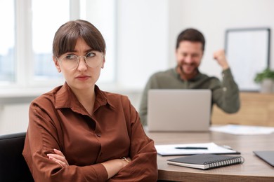 Photo of Woman feeling jealous of her colleague's success in office, selective focus
