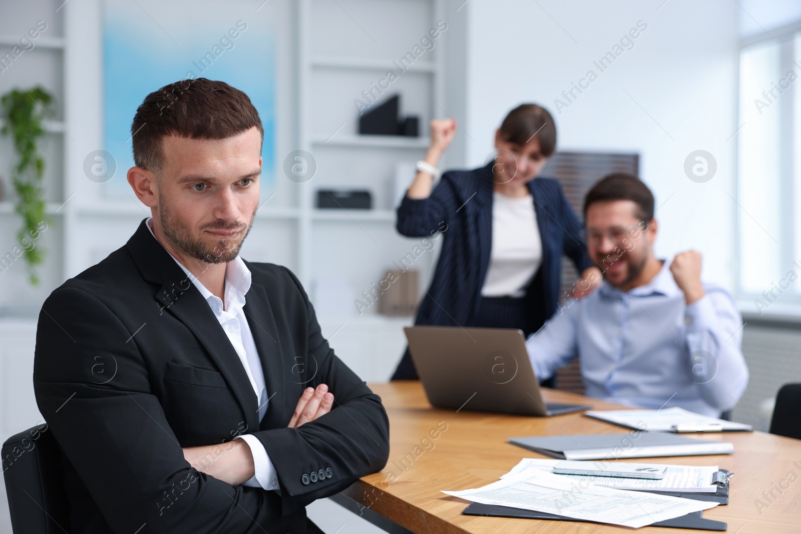 Man feeling jealous of his colleague's success in office, selective focus Photo of Man feeling jealous of his colleague's success in office, selective focus