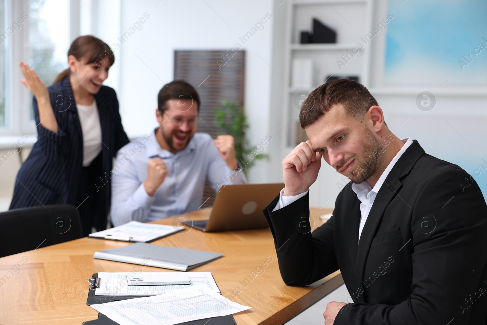 Man feeling jealous of his colleague's success in office, selective focus Photo of Man feeling jealous of his colleague's success in office, selective focus