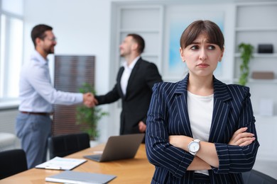 Photo of Woman feeling jealous of her successful colleague receiving congratulations in office, selective focus