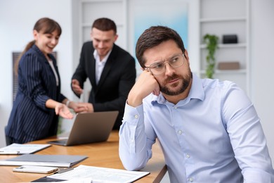 Photo of Man feeling jealous of his colleague's success in office, selective focus