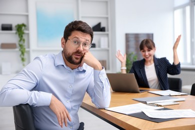 Photo of Man feeling jealous of his colleague's success in office, selective focus