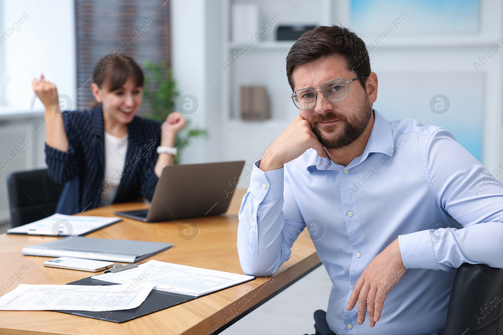 Man feeling jealous of his colleague's success in office, selective focus Photo of Man feeling jealous of his colleague's success in office, selective focus