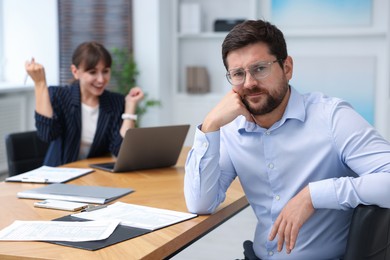 Photo of Man feeling jealous of his colleague's success in office, selective focus
