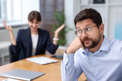 Photo of Man feeling jealous of his colleague's success in office, selective focus