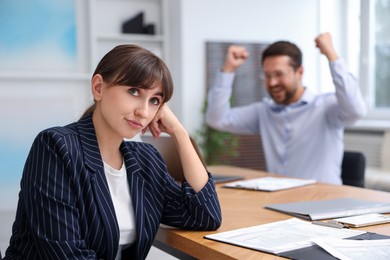 Photo of Woman feeling jealous of her colleague's success in office, selective focus