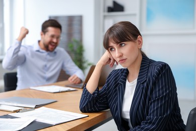 Photo of Woman feeling jealous of her colleague's success in office, selective focus