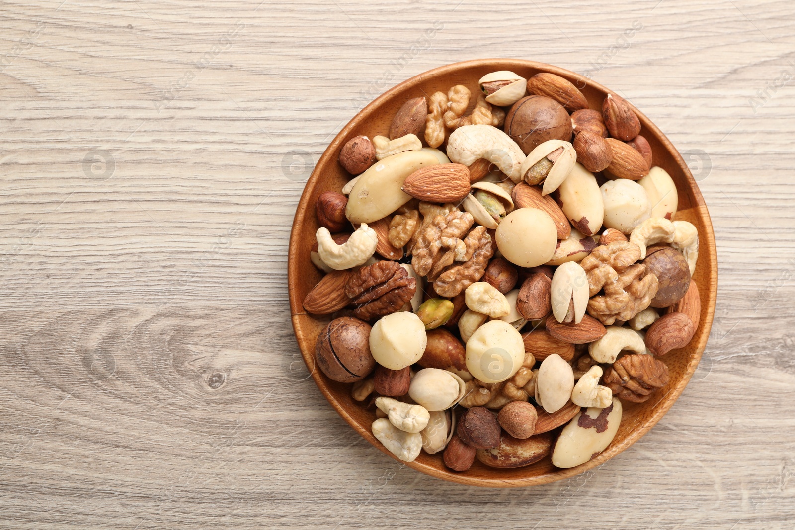 Photo of Mix of different nuts on wooden table, top view. Space for text