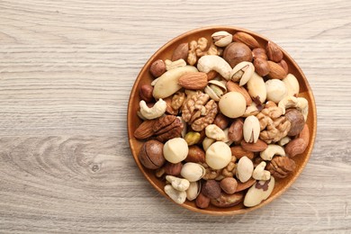 Photo of Mix of different nuts on wooden table, top view. Space for text