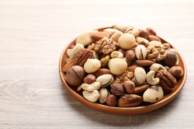 Photo of Mix of different nuts on wooden table, closeup. Space for text