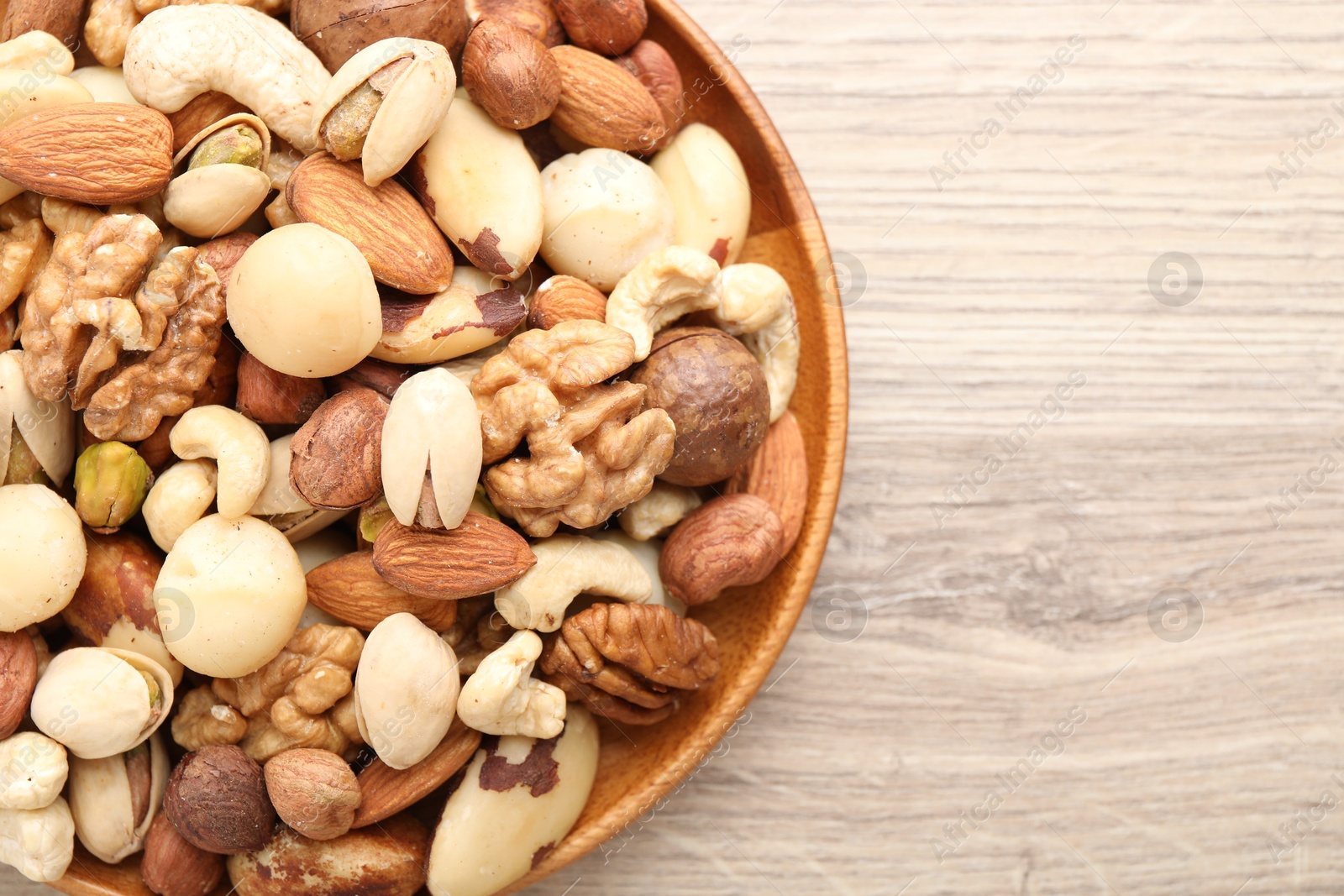 Photo of Mix of different nuts on wooden table, top view. Space for text