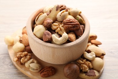 Photo of Mix of different nuts in bowl on wooden table, closeup