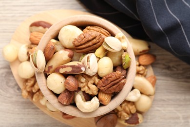 Photo of Mix of different nuts in bowl on wooden table, top view