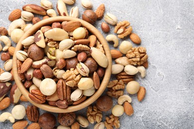 Photo of Mix of different nuts on grey textured table, top view