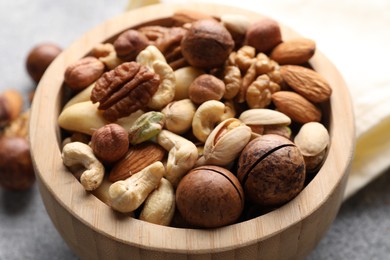 Photo of Mix of different nuts in bowl on grey table, closeup